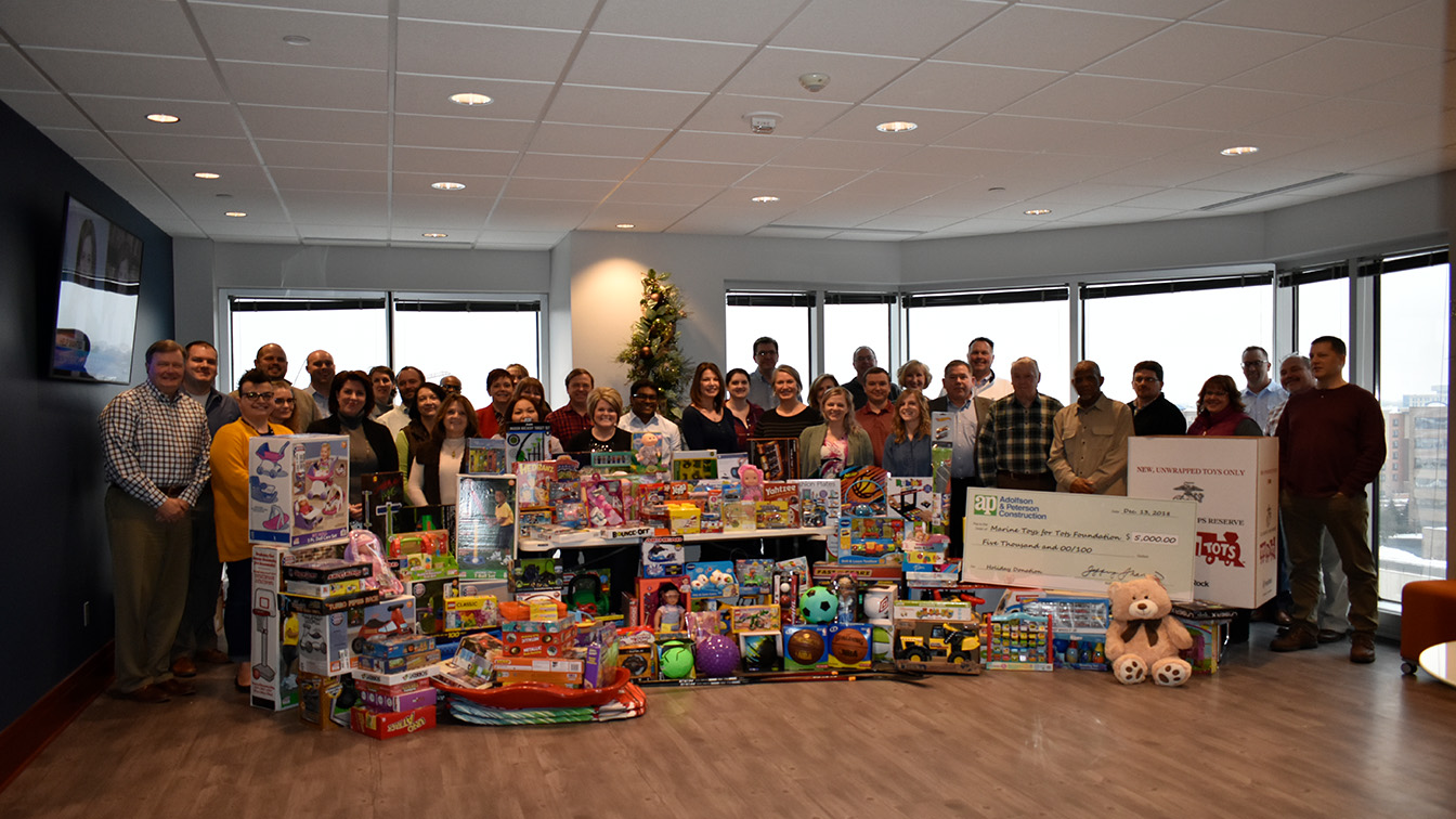 Group of people standing behind toys at toy drive