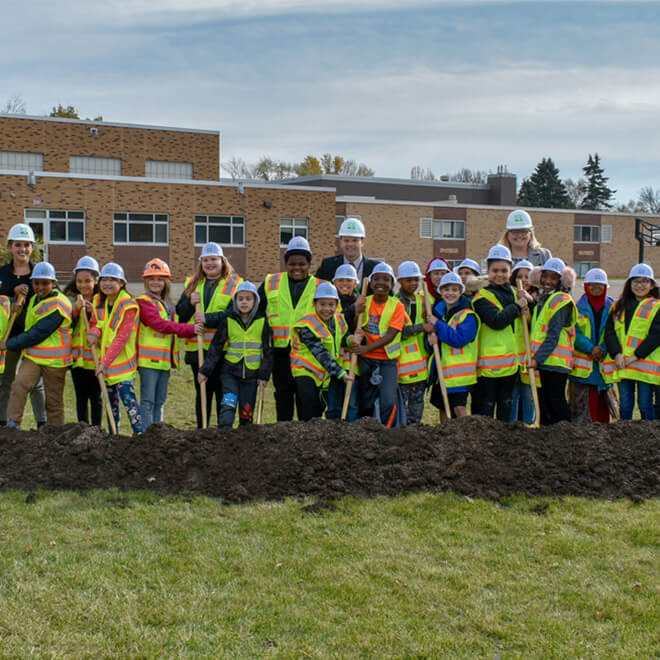 Group of kids breaking ground in front of building